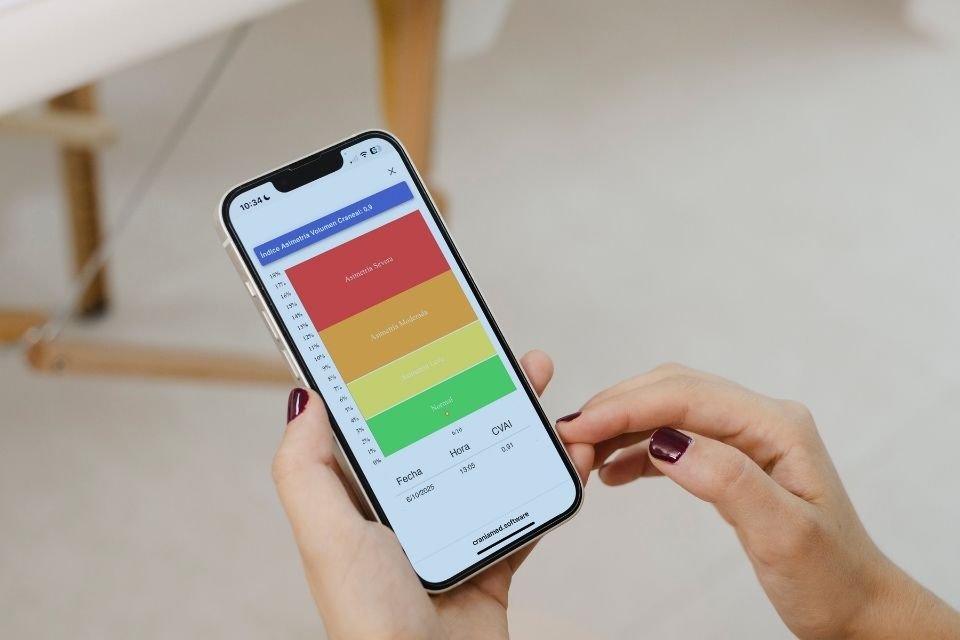 Las manos de una fisio pediátrica sujetando un móvil en el que podemos ver la gráfica de evolución de un bebé