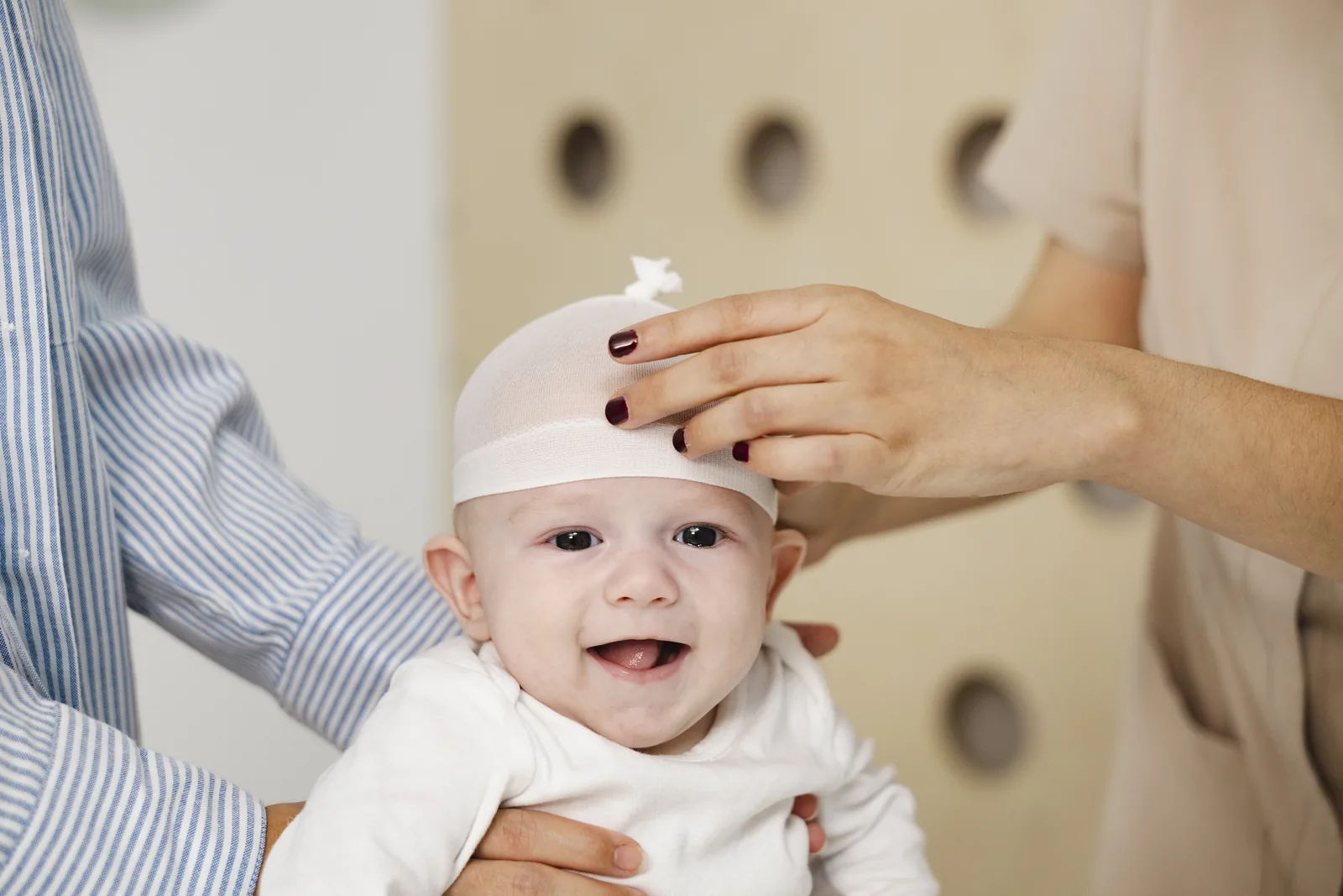 Foto de un bebé con el gorro de craniamed sonriente y mirando a cámara